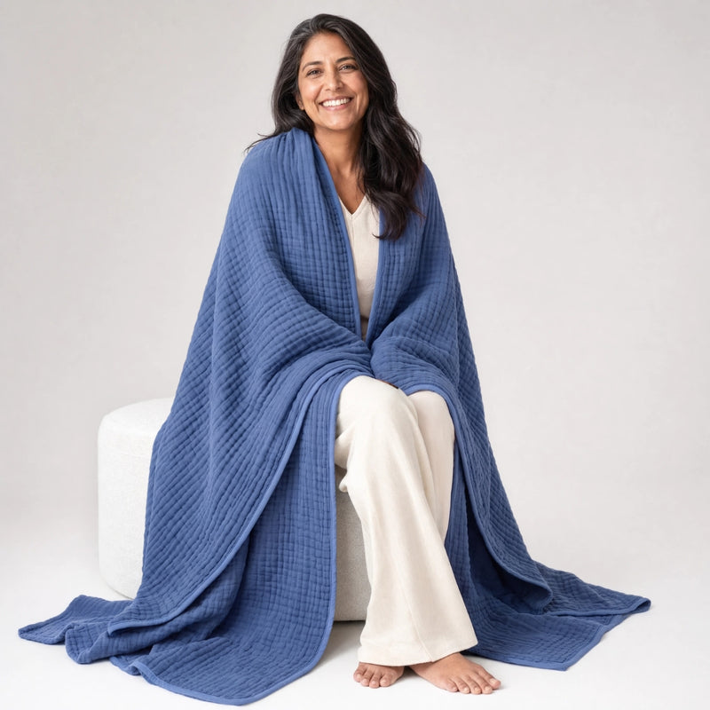 Woman on a pouf with the Muslin Blanket in Navy draped to the floor